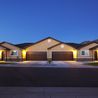 Row of townhomes with lit garages and mountain backdrop at dusk