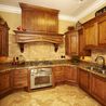 Kitchen with custom wood cabinetry, decorative range hood, and stainless refrigerator